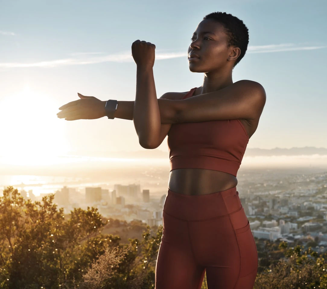 Woman in activewear with a cityscape backdrop at sunset